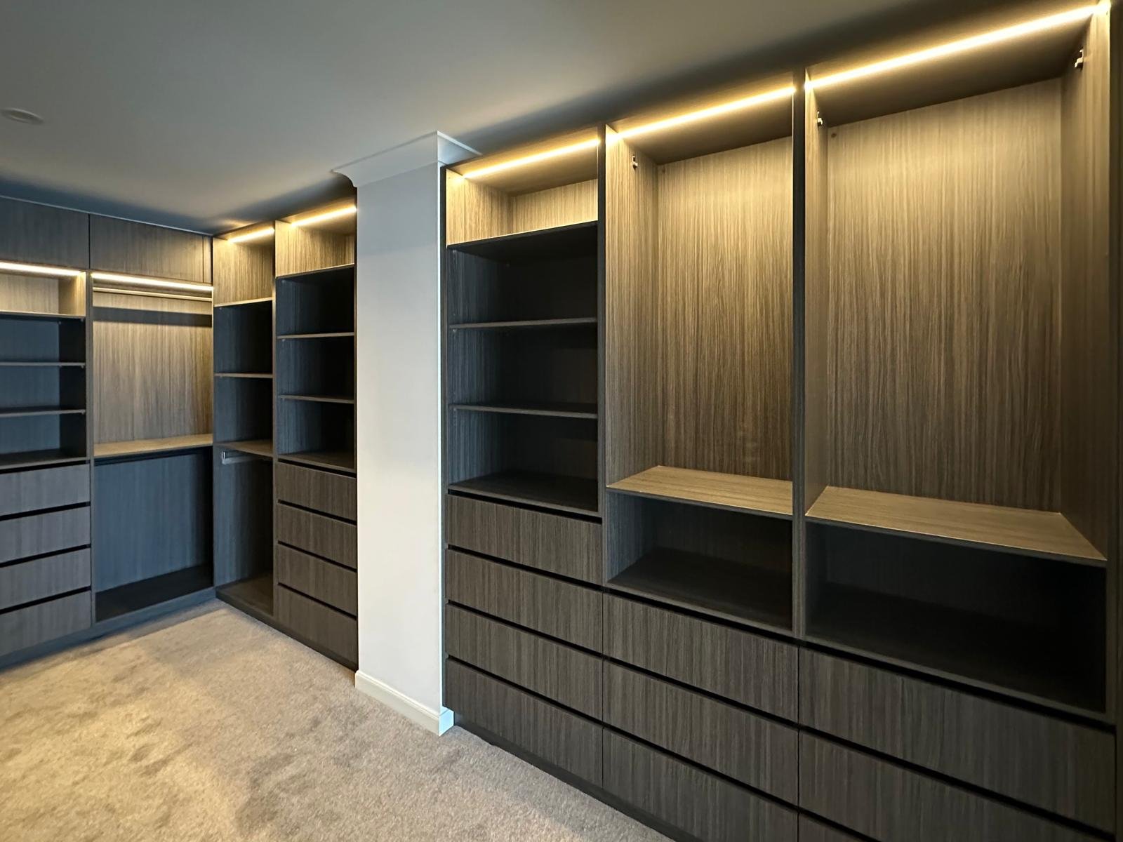 Custom wardrobe shelving and drawers illuminated by concealed LED strips